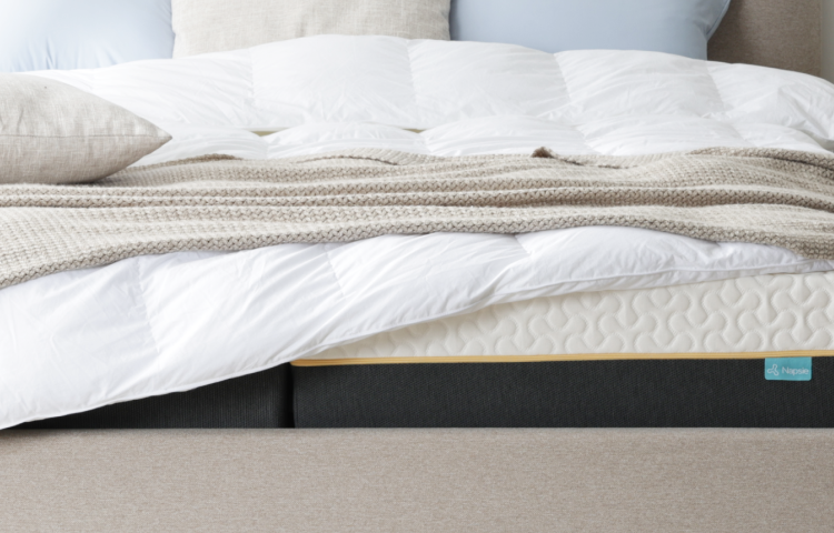 Moderne Matratze mit weißer Bettwäsche und Strickdecke, ideal für erholsamen Schlaf